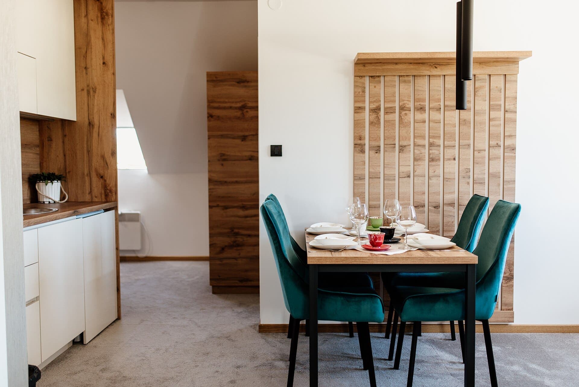 Coin repas : table en chêne, chaises en velours vert et claustra en bois